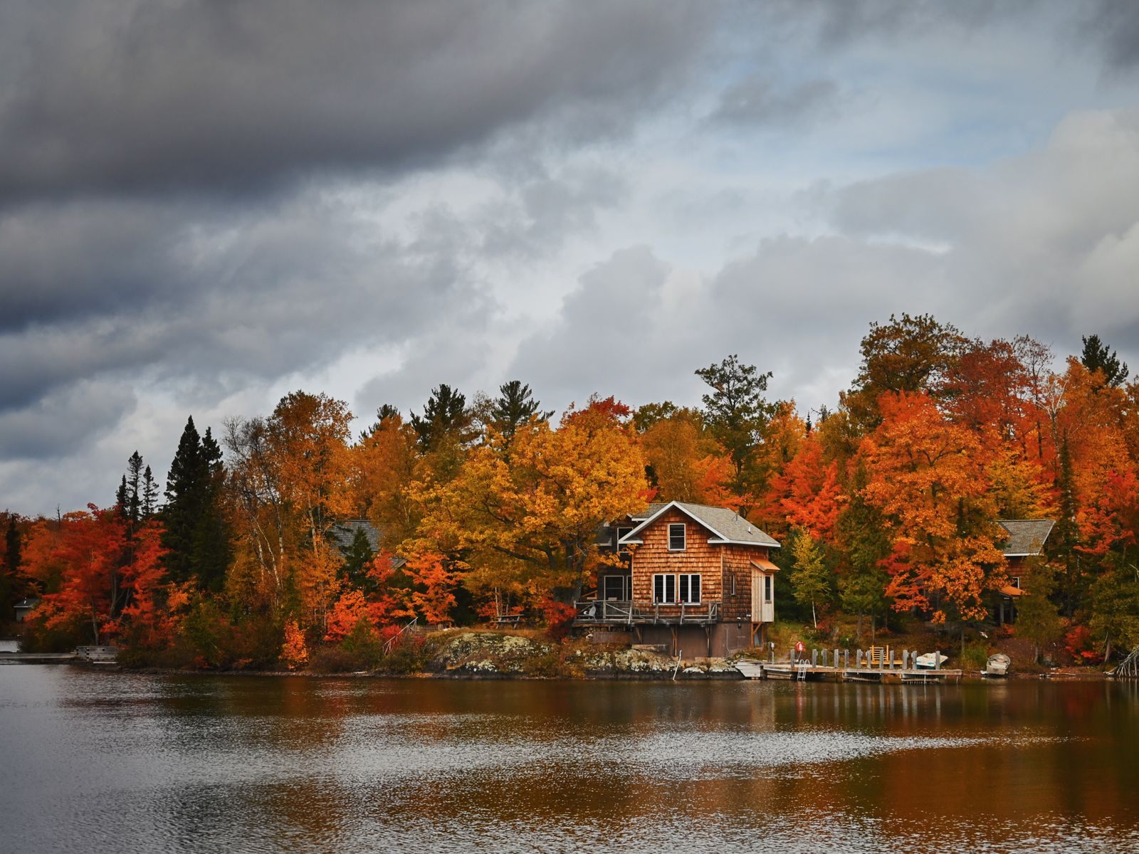 A lakeside cabin among orange and red fall trees, the kind of lake country that makes up many Minnesota vacation spots
